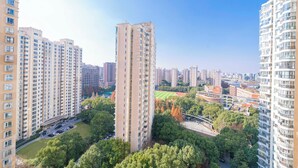 Un edificio residencial de gran altura con varios pisos, rodeado de vegetación y otros edificios.