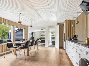 Una cocina moderna con comedor, paneles de madera y un ventanal grande.