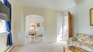 A living room with a floral sofa, a wooden coffee table, and a dining area with a table and chairs. - Main St Apt w/ Pool Table & Sauna in Westernport! (Westernport)