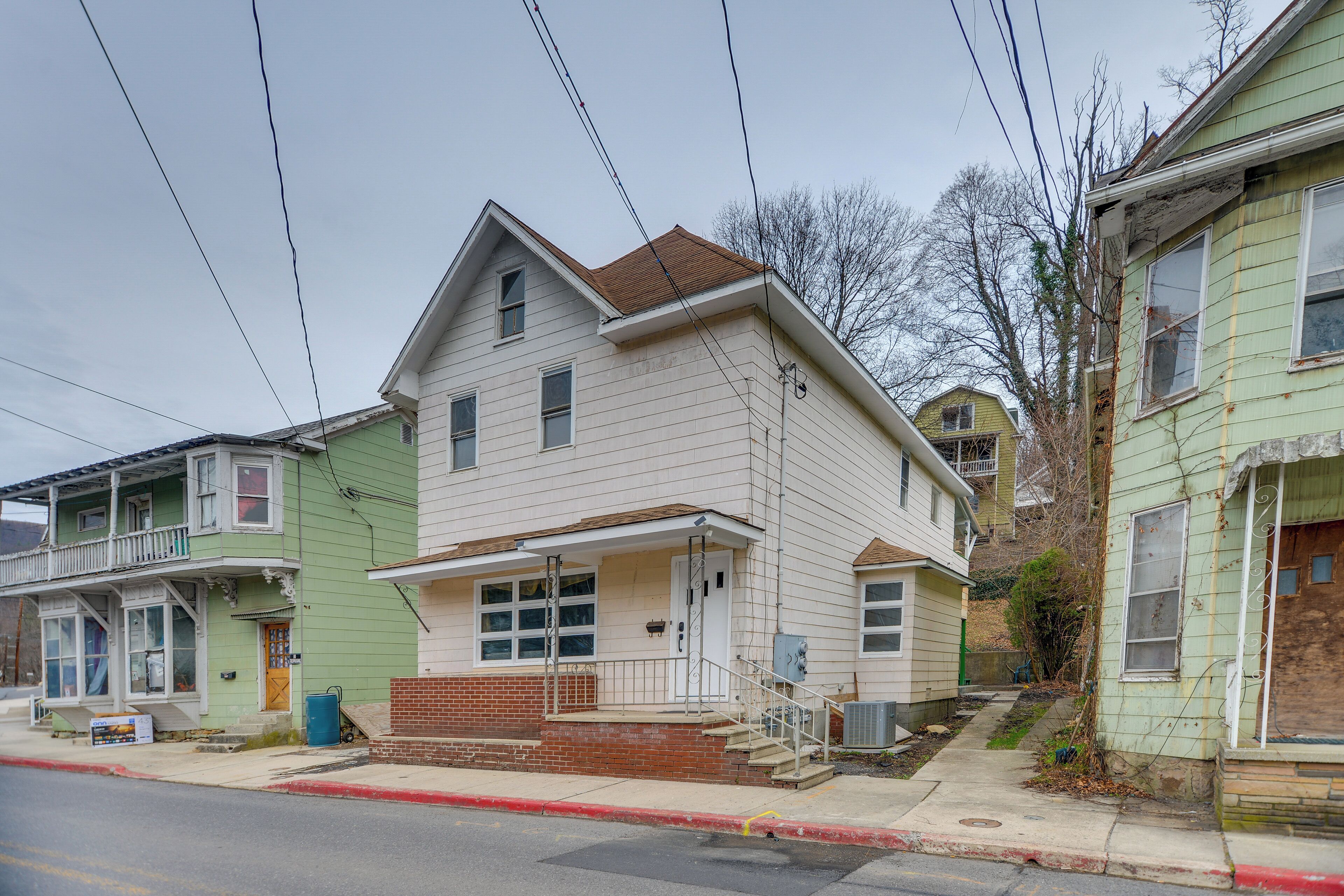 A two-story house with a front porch, a brick foundation, and a visible front yard.