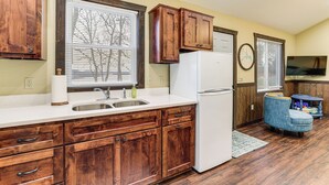 A kitchen with wooden cabinets, a white refrigerator, and a sink. - Stunning Views! Table Rock Lake Cabin Near Marina (Shell Knob)