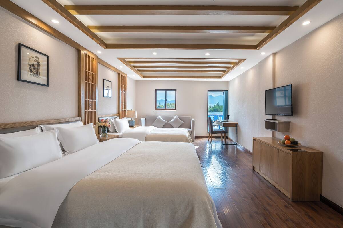 Habitación de hotel con dos camas, un escritorio, un televisor y vistas al exterior.