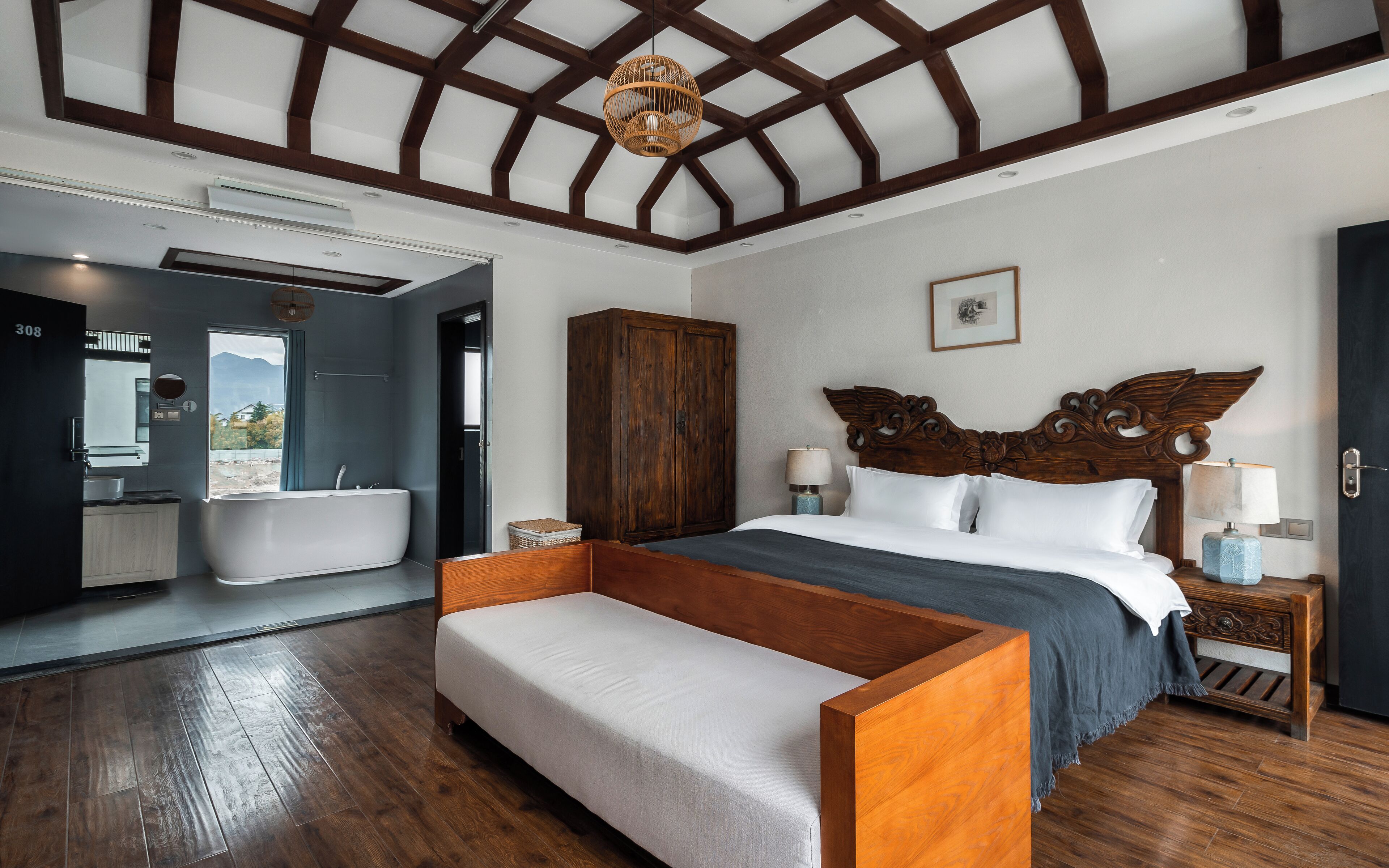 A modern bedroom with a wooden bed, a bench, a large wardrobe, and a bathroom with a bathtub.