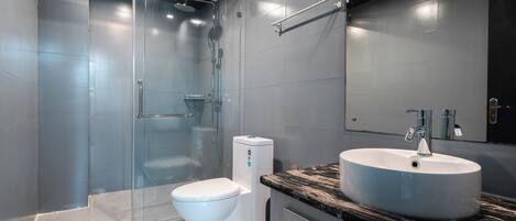 Une salle de bain moderne avec une douche à parois de verre, des toilettes blanches et un lavabo sur un plan de travail en marbre.