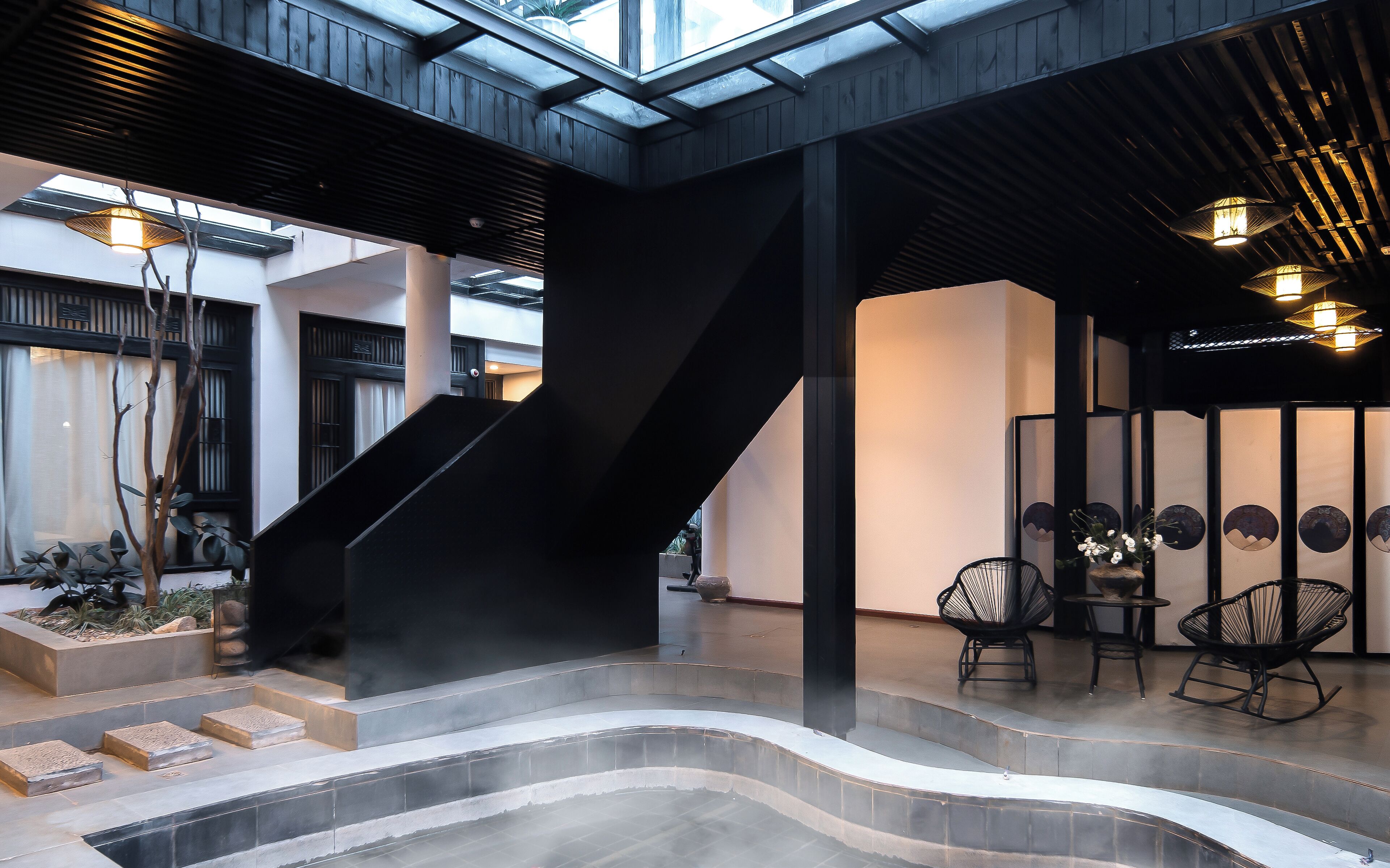 A modern interior with a curved hot tub, black staircases, and a seating area with chairs.