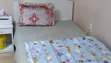 A small, neatly arranged bedroom with a bed, a pillow, a bedside table with a lamp, and an air conditioning unit mounted on the wall.