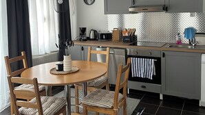 A modern kitchen with grey cabinets, a round wooden table, and a dining area with chairs. - Beautiful vacation apartment in the Altmark (Goldbeck)
