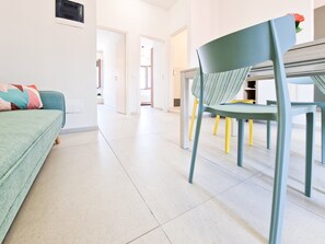 Une pièce moderne comprenant un canapé, une table à manger avec des chaises et un couloir menant à une autre pièce.