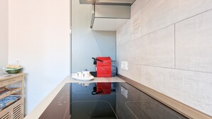 A modern kitchen with a black countertop, a red appliance, and a basket on a wooden shelf. - Porta A Mare Home Apartment with Air Conditioning (Portoferraio)