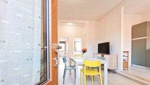 A modern interior with a dining area, a television, and a kitchen. - Porta A Mare Home Apartment with Air Conditioning (Portoferraio)