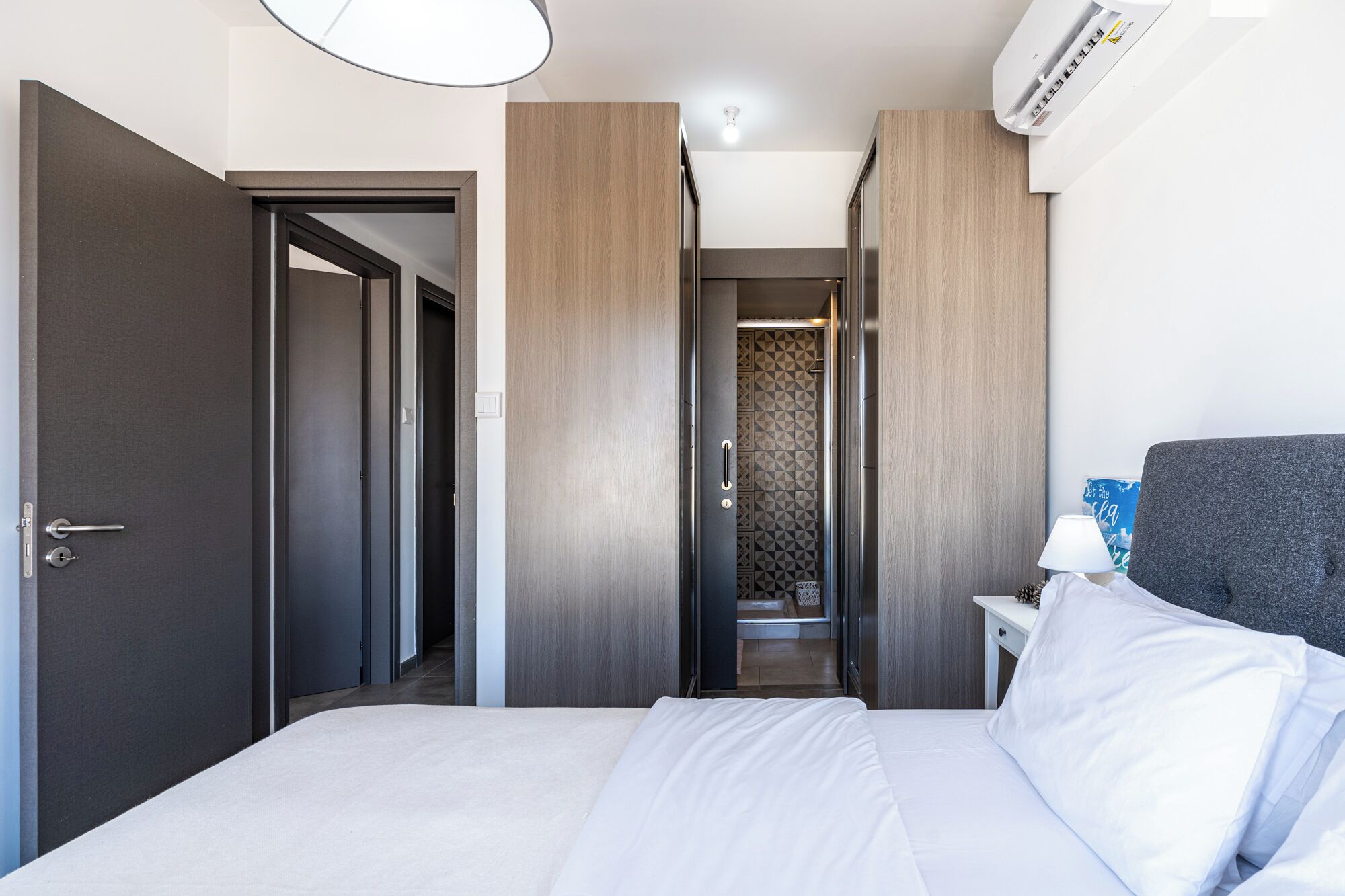 A hotel room with a bed, a nightstand, a lamp, and a wardrobe.