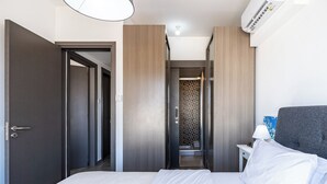 Una habitación de hotel con cama, mesita de noche, lámpara y armario.