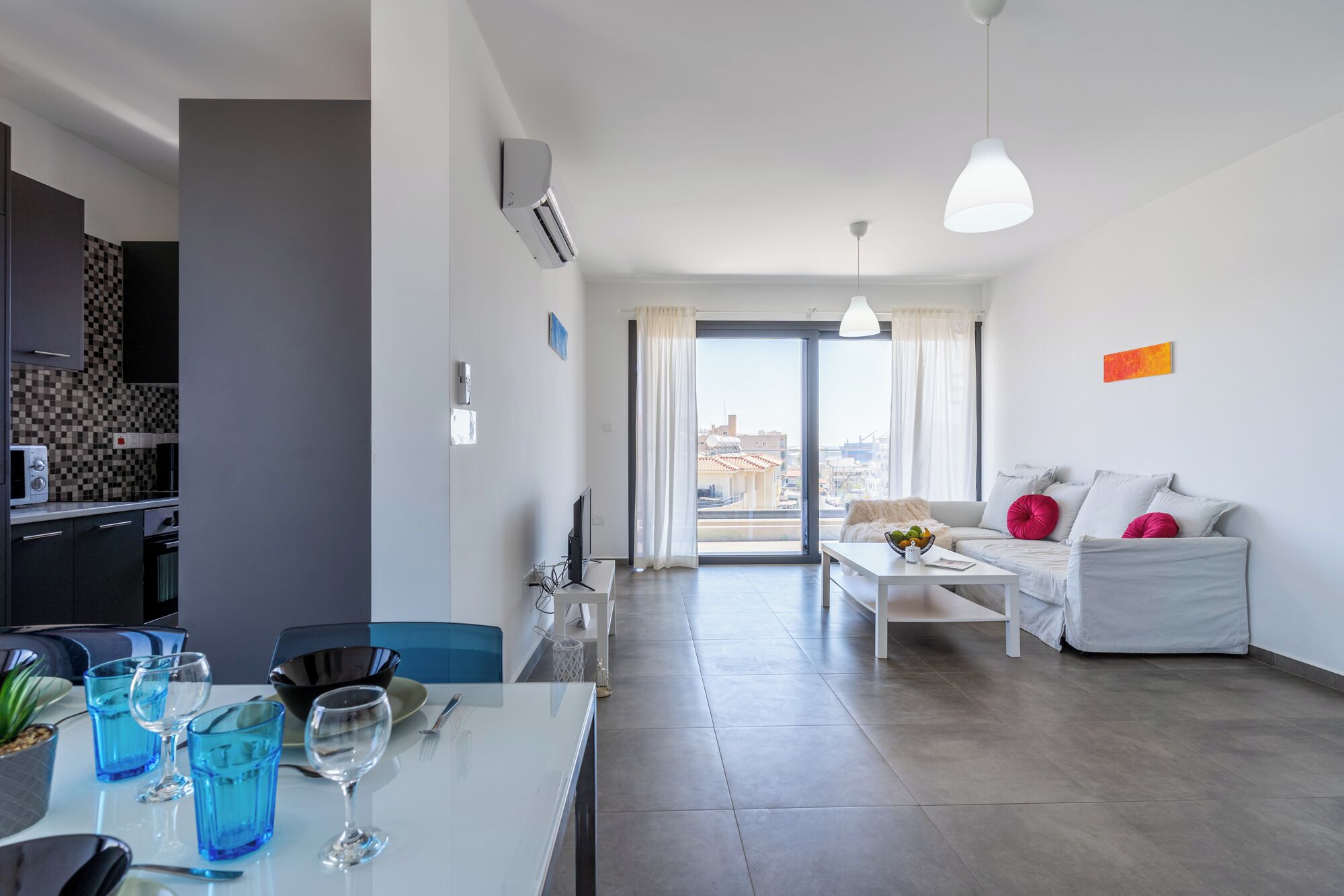 A modern apartment with a dining area, kitchenette, and living space.