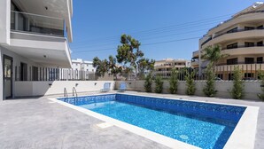 Una piscina rectangular con superficie de agua cristalina y azul, rodeada por una solería.