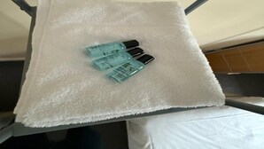 Ein weißes Handtuch auf einem Metallgestell mit drei Duschgels.