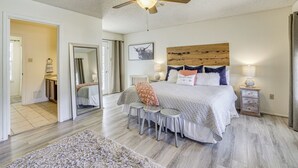 Ein Schlafzimmer mit einem Bett, einem Deckenventilator, einem Nachttisch und einem Spiegel.