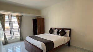 A bedroom with a bed, a wardrobe, and a window with curtains. - BBR Holiday Home (Ooty)