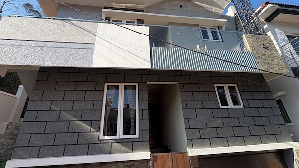 A two-story house with a sloped roof, a balcony, and a garage. - BBR Holiday Home (Ooty)