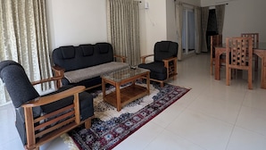 A living room with a sofa, two armchairs, a coffee table, and a dining table with chairs. - BBR Holiday Home (Ooty)