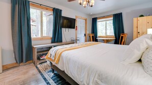Ein Schlafzimmer mit einem Bett, einem Schreibtisch, einem Stuhl, einem Fernseher und einem Deckenventilator.