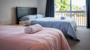 A hotel room with two beds, one with a pink bedspread and the other with a blue bedspread. - Parkside Elegance on Puoro St Near Shopping Centre (Auckland)