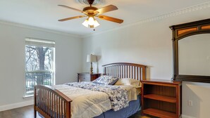A bedroom with a wooden bed, a nightstand, a dresser, a ceiling fan, and a large mirror. - 11 Mi to Dtwn Dallas: Charming Home w/ Deck & Yard (Irving)