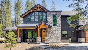 Une maison moderne avec une façade en pierre, de grandes fenêtres et un porche en bois.