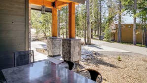 Un espace de restauration en plein air avec une table et des chaises, des piliers en pierre et une vue sur une zone boisée.