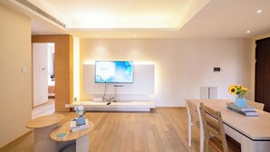 A modern hotel lobby with a flat-screen TV mounted on a wall, a reception desk, a dining area with a table and chairs, and a wooden floor. - Tyms Gubei 3BR Family Apt at Mingdu City (Shanghai)
