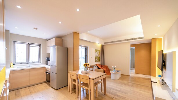 A modern kitchen with a dining area, wooden flooring, and a flat-screen TV mounted on the wall. - Tyms Gubei 3BR Family Apt at Mingdu City (Shanghai)