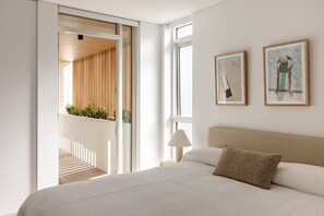 A bedroom with a bed, a nightstand, a lamp, and two framed artworks on the wall. - Kailani 301: Designer Waterfront Apartment (Batemans Bay)