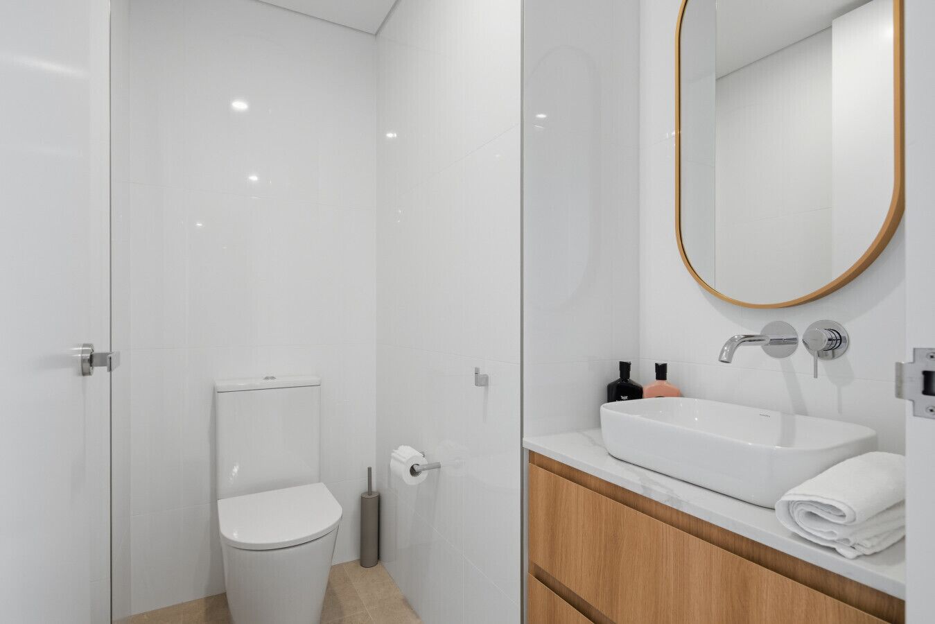 Een moderne badkamer met toilet, bidet en een wastafelmeubel met wastafel en spiegel.