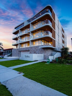 A modern multi-story hotel with a stone facade, multiple balconies, and a well-maintained lawn. - Kailani 202: Uninterrupted Bay & Marina Views (Batemans Bay)