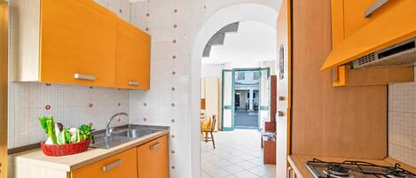 Una cocina con gabinetes naranjas, una estufa a gas y un fregadero.