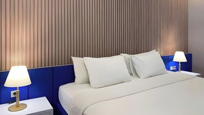 A hotel room with a bed, two bedside tables, and a wall with vertical wooden slats. - Madina inn Hotel & Hostel Yogyakarta (Yogyakarta)