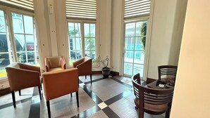 A spacious room with large windows, a checkered floor, and a dining area with wooden chairs and a table. - Madina inn Hotel & Hostel Yogyakarta (Yogyakarta)