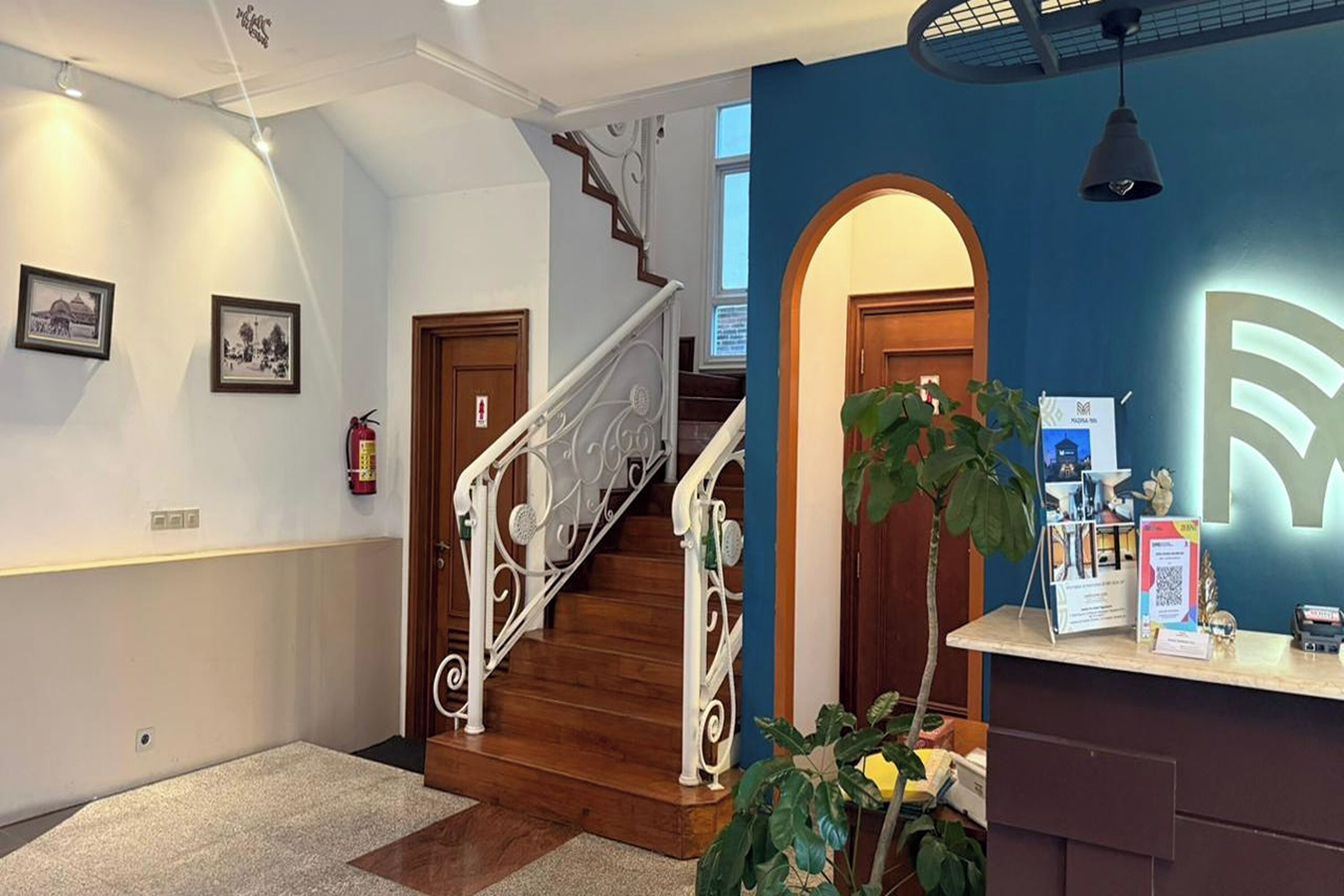 A reception area with a wooden staircase, a reception desk, and framed pictures on the wall.