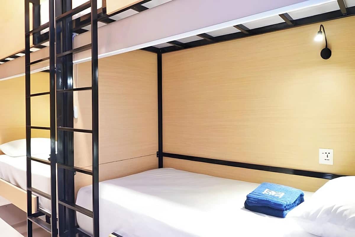 A bunk bed room with a ladder, a single bed, and a wall-mounted light fixture.