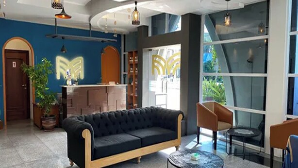 A modern hotel lobby with a black sofa, a reception desk, and a seating area with chairs and a small table. - Madina inn Hotel & Hostel Yogyakarta (Yogyakarta)
