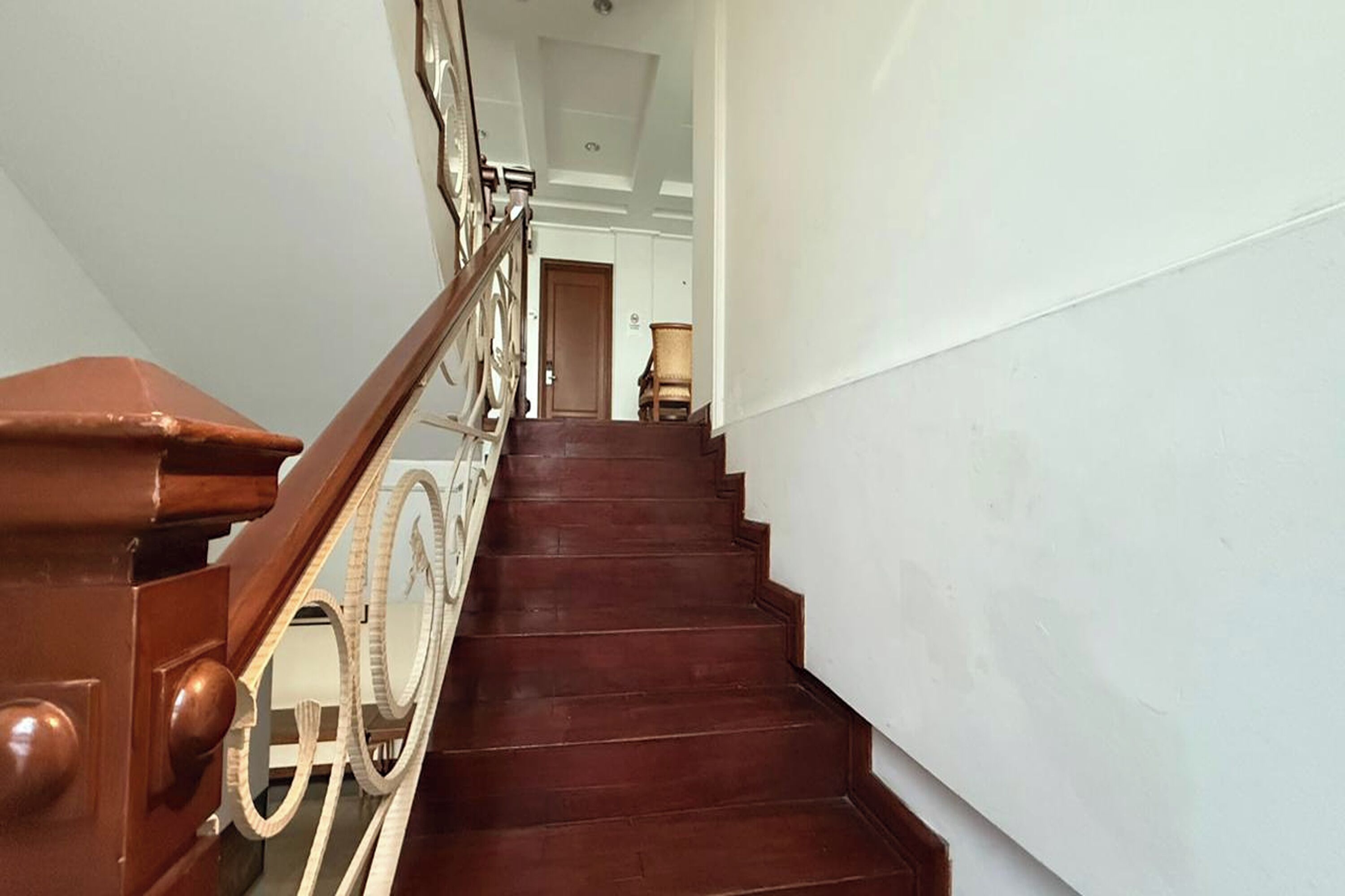 Eine Holztreppe mit Handlauf und einer Tür am oberen Ende.
