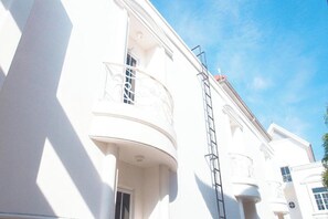 Ein weißes Gebäude mit Balkonen und einem sichtbaren Fenster.
