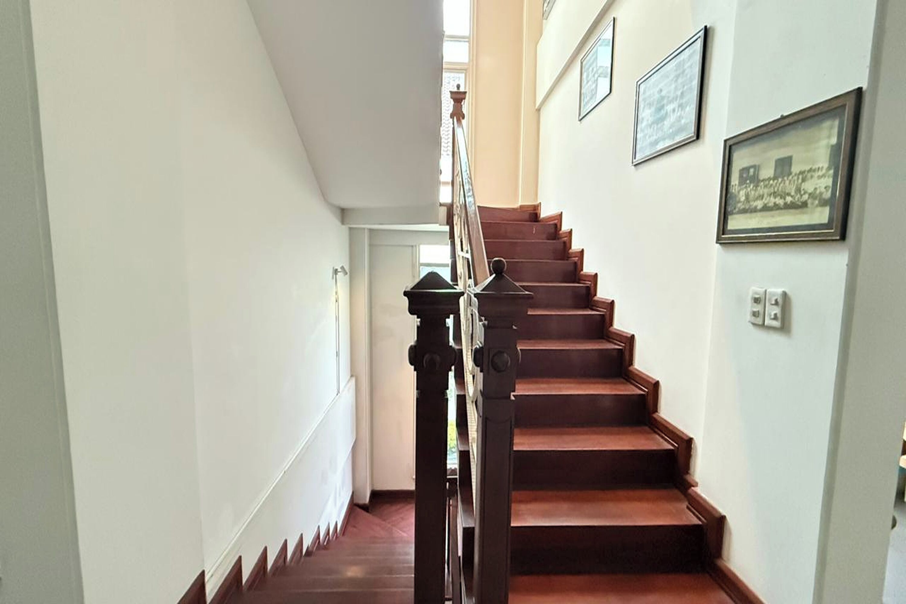 A staircase with wooden steps and a wooden handrail, leading to an upper floor.