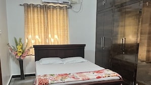 Un dormitorio con cama, armario, ventilador de techo y aire acondicionado.
