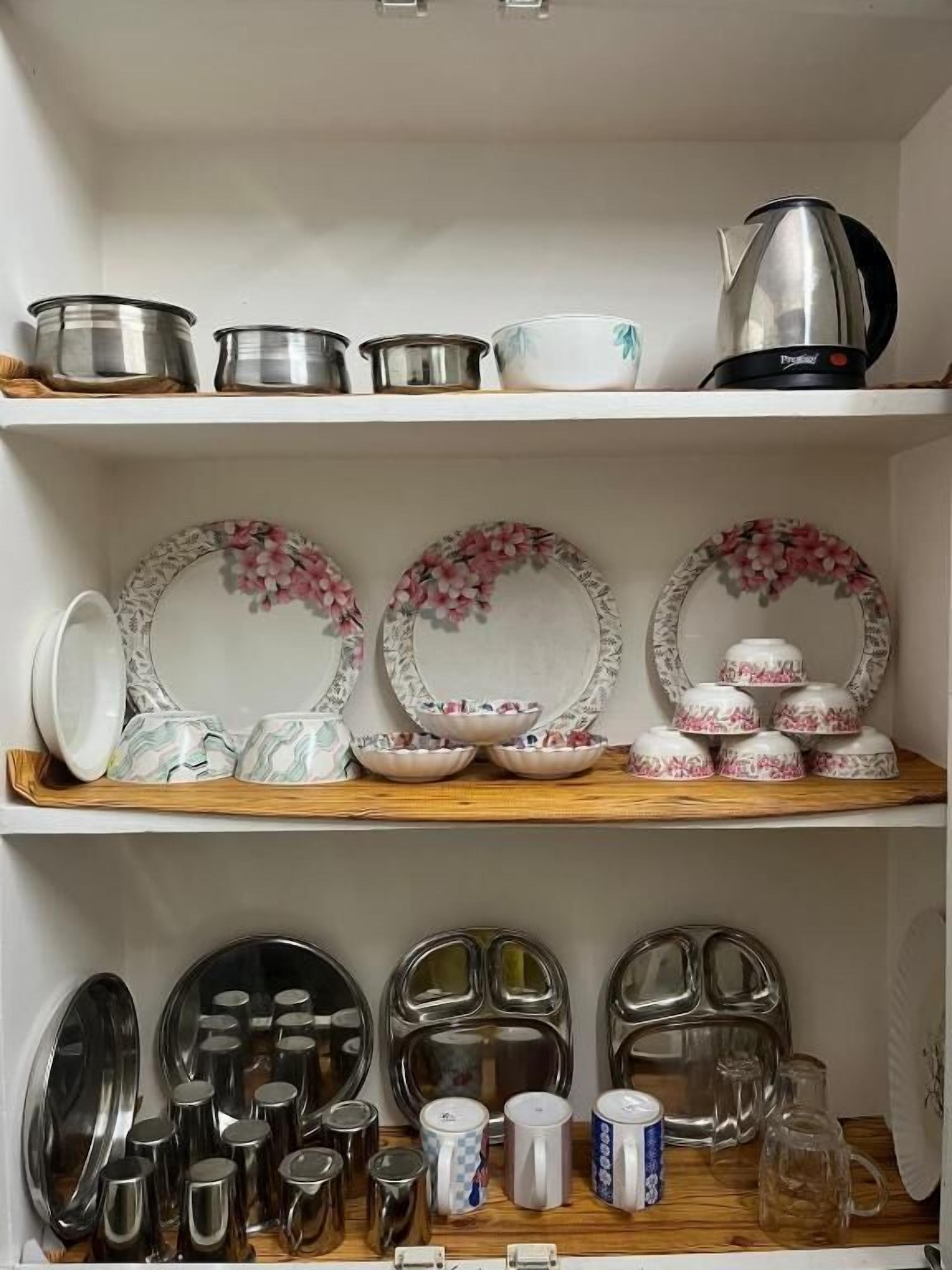 A kitchen shelf with various cookware, including pots, pans, and a kettle.