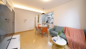 A modern living room with a sofa, a dining table with chairs, a coffee table, and a kitchen in the background. - Tyms Tianshan 2BR near Riverside Park (Shanghai)