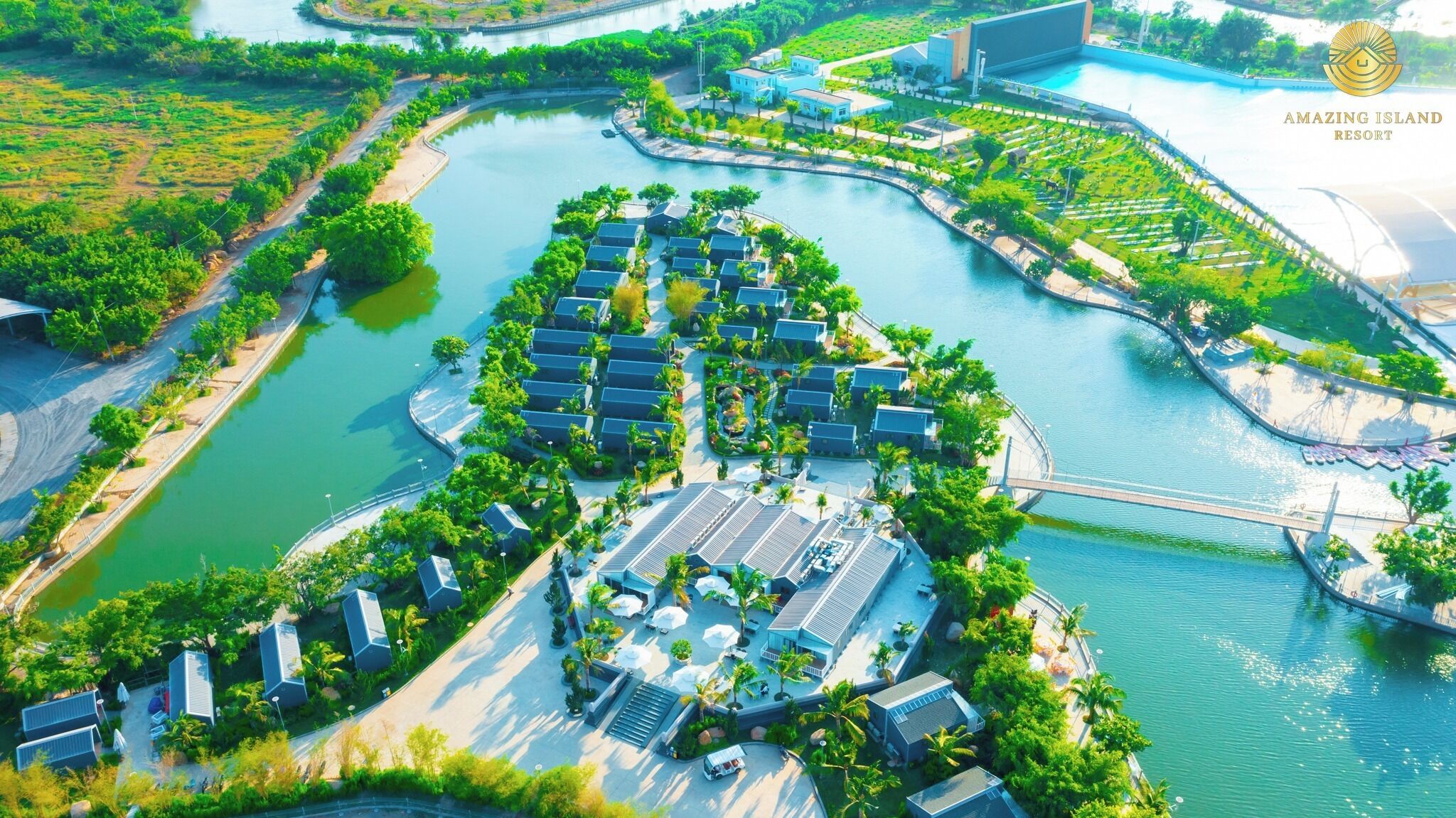 An aerial view of a resort with multiple buildings arranged around a central water body, connected by pathways and bridges.