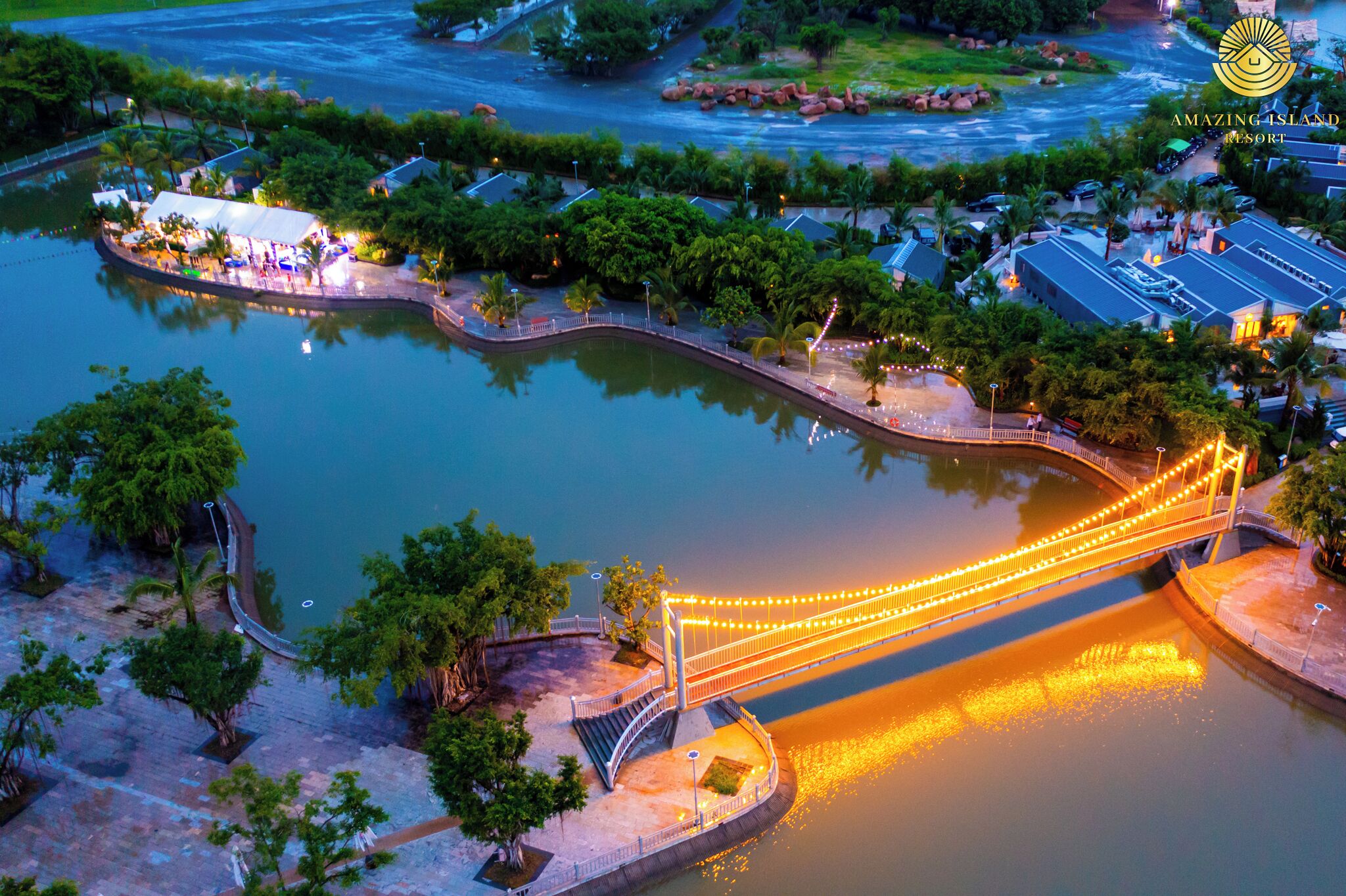 Luftaufnahme eines Resorts mit einer Brücke über dem Wasser, einem Steg und einem gut beleuchteten Weg.
