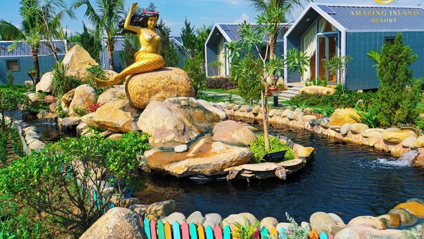 A resort with a large golden statue, a pond, and modern buildings. - Amazing Island Resort (Long Hung)