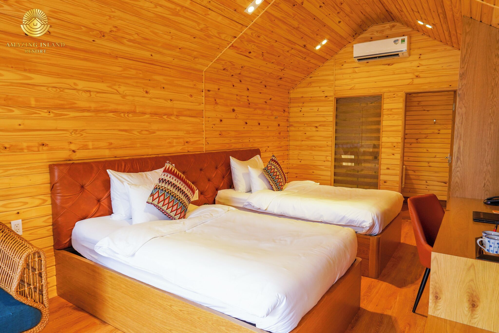 Ein holzgetäfeltes Zimmer im Blockhausstil mit zwei Betten, einer Holzbalkendecke und einem kleinen Tisch mit Stuhl.
