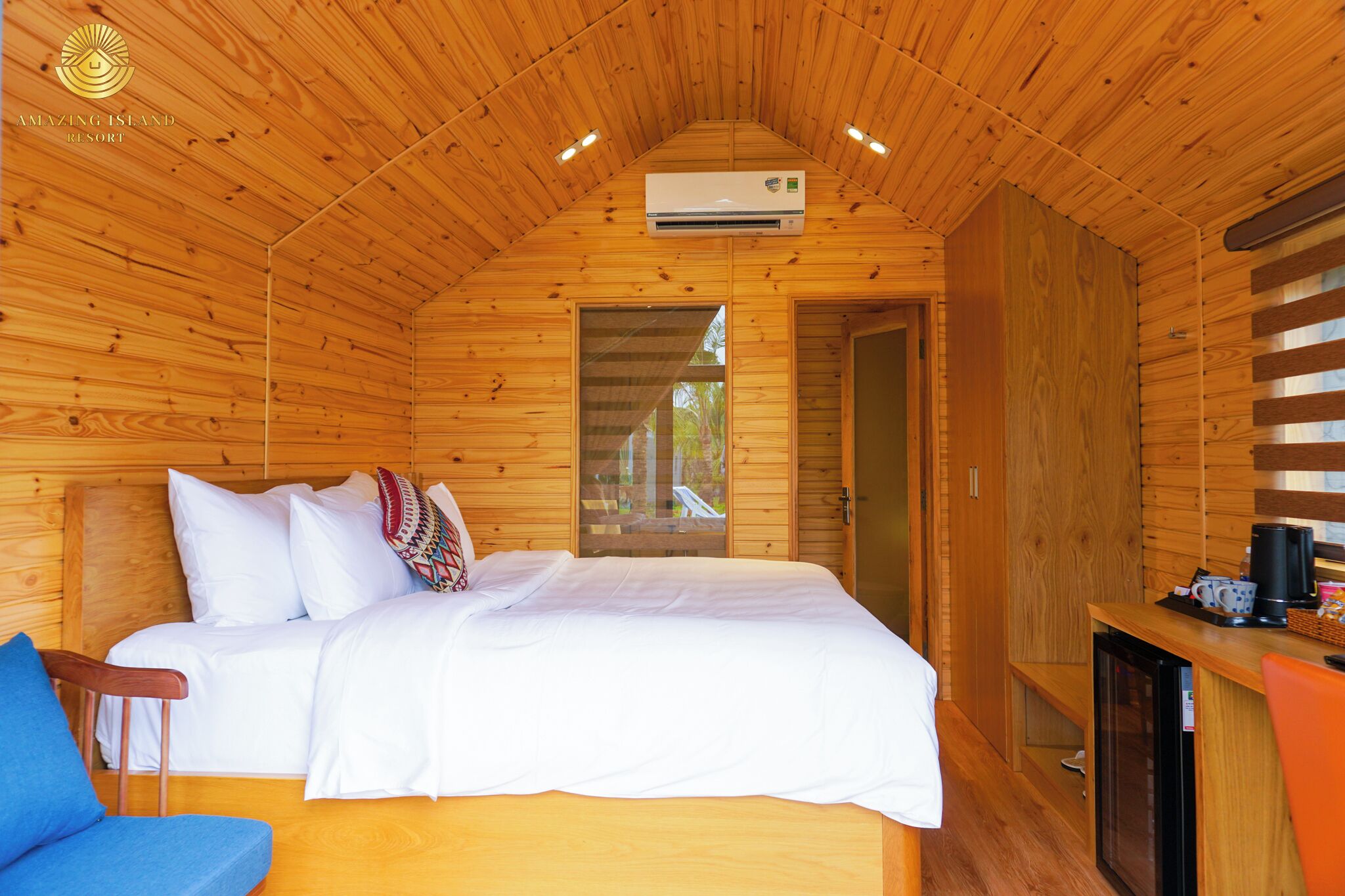 A wooden cabin room with a bed, a desk, and a window.